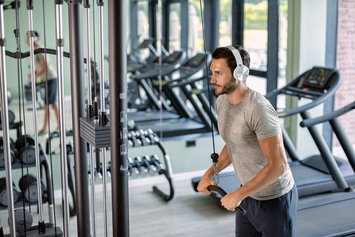 Young athlete strengthening his biceps on exercise machine in a gym.