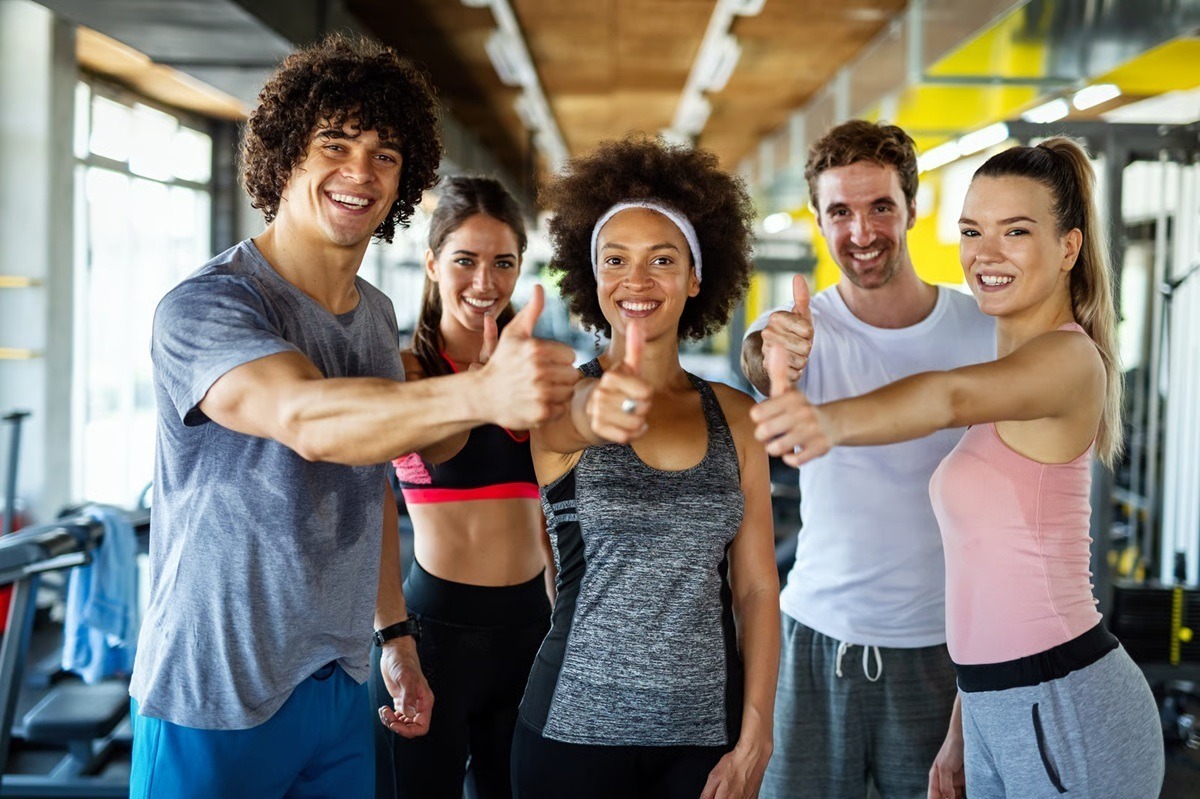 Group of people wearing gym wear smiling and giving thumps-up