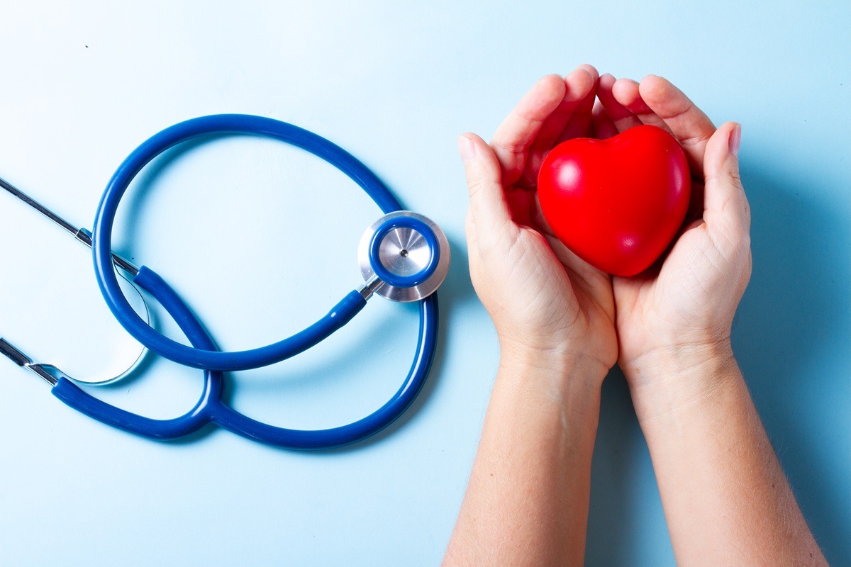 Two hands holding heart and stethoscope on blue. Two hands holding heart and stethoscope on blue.