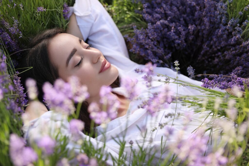 A woman rests in a field of blooming lavender, enjoying the beauty and tranquility of the purple flowers around her.