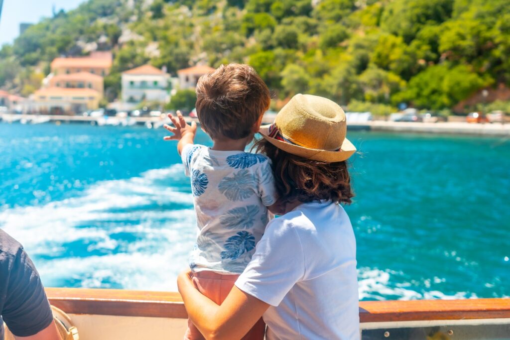 A family of four on a boat, gazing out at the vast sea under a clear blue sky