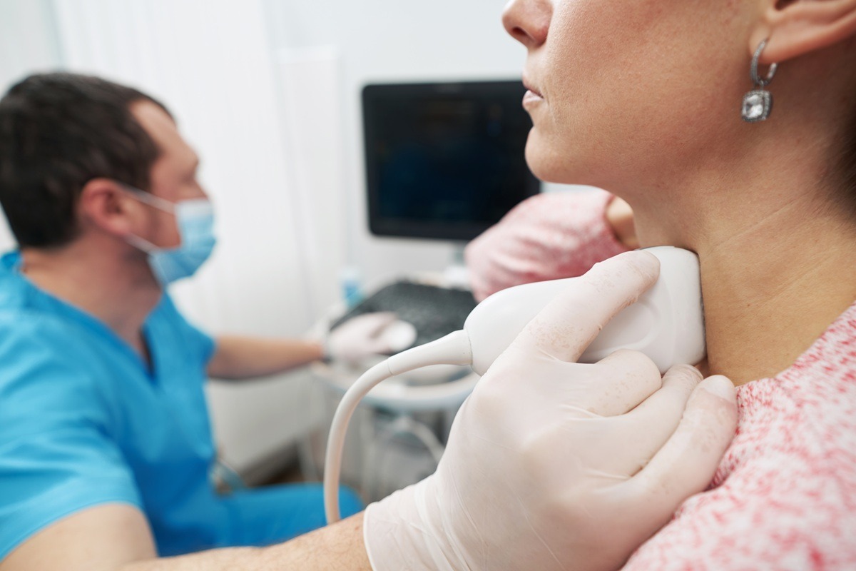 Caucasian woman at endocrinologist appointment undergoing thyroid ultrasound scan. 