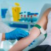 Medical worker with PPE taking blood sample from patient in a hospital