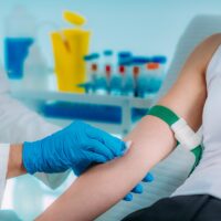 Medical worker with PPE taking blood sample from patient in a hospital