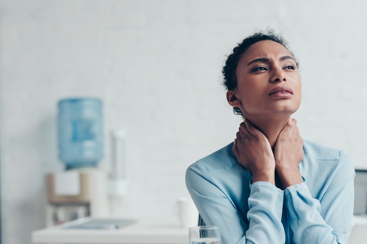A woman suffering from neck pain in office.