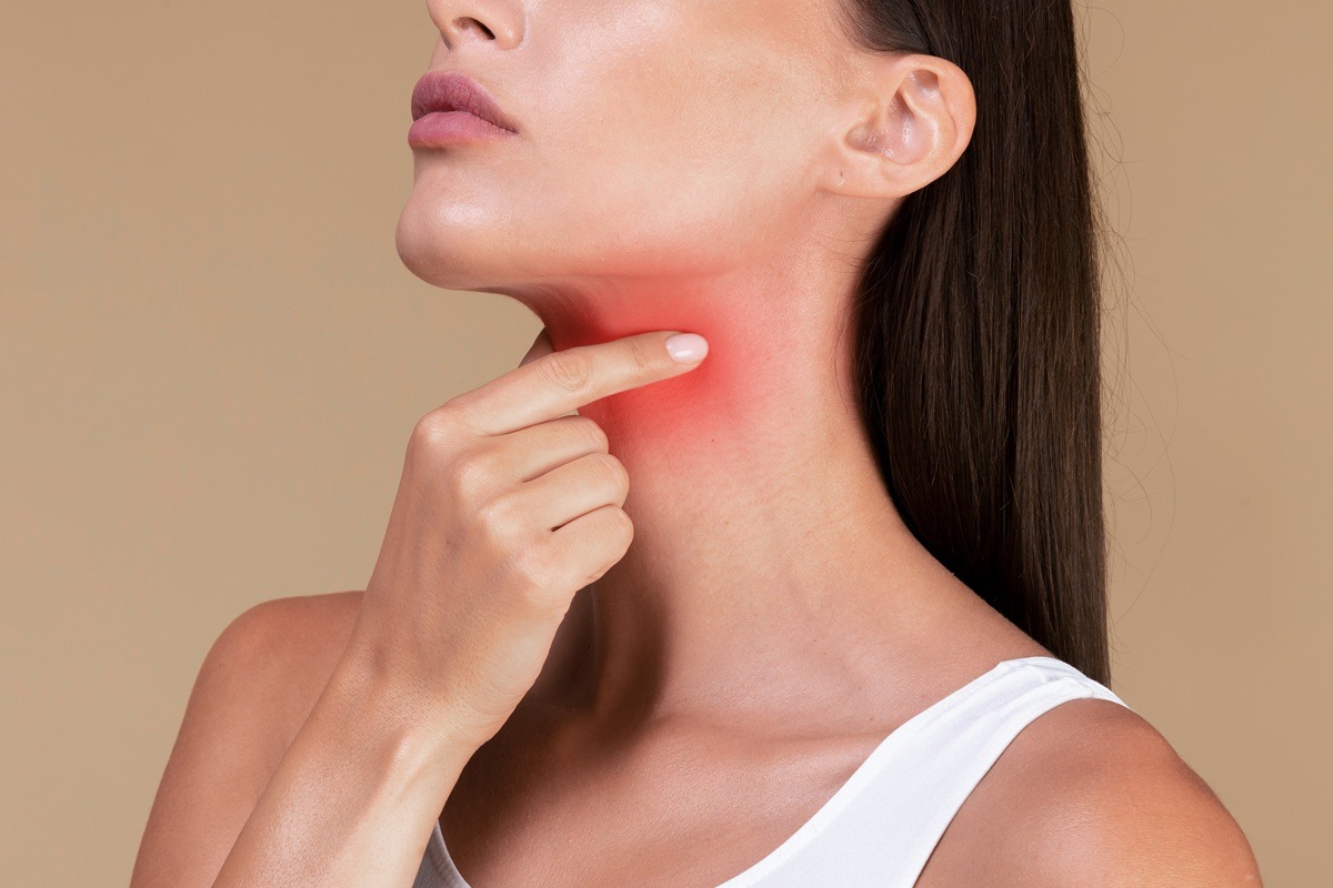 A lady suffering from sore throat, touching neck with hand, inflamed red zone.