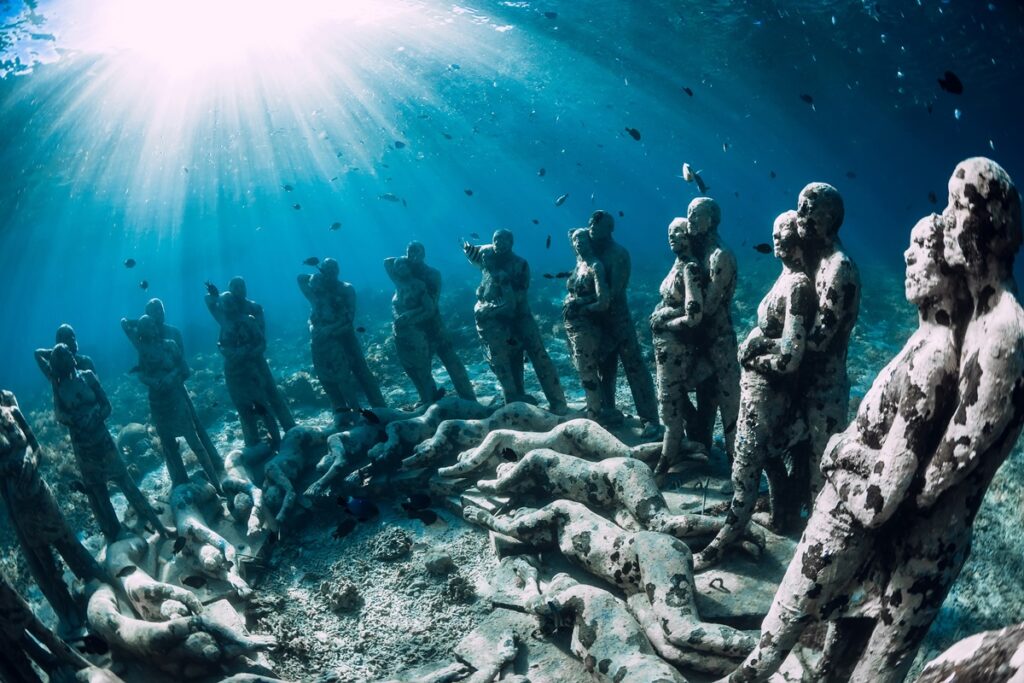 A collection of stone sculptures submerged in water, highlighting artistic details and marine surroundings.