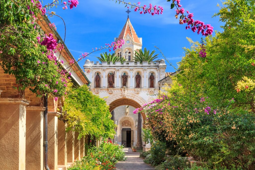 Exterior view of the Abby on the Île Saint-Honorat in Cannes, featuring intricate architectural details and vibrant landscaping.