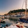 Scenic view of Nice harbor at sunset with yachts and colorful buildings, capturing the serene atmosphere of the French Riviera.