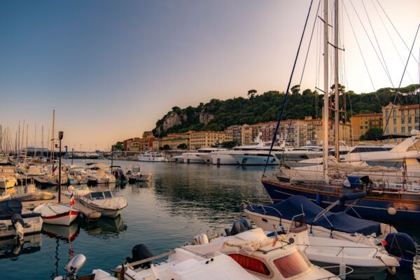 Scenic view of Nice harbor at sunset with yachts and colorful buildings, capturing the serene atmosphere of the French Riviera.