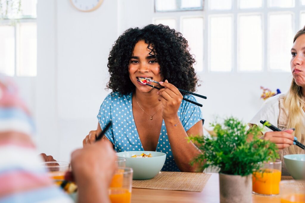 Multiethnic group of young friends meeting at home and eating poke bowls - Multiracial happy people bonding while having lunch.
